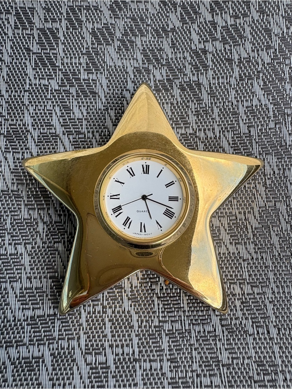 Gold-Tone star shape decorative table clock with a white dial and Roman Numeral.